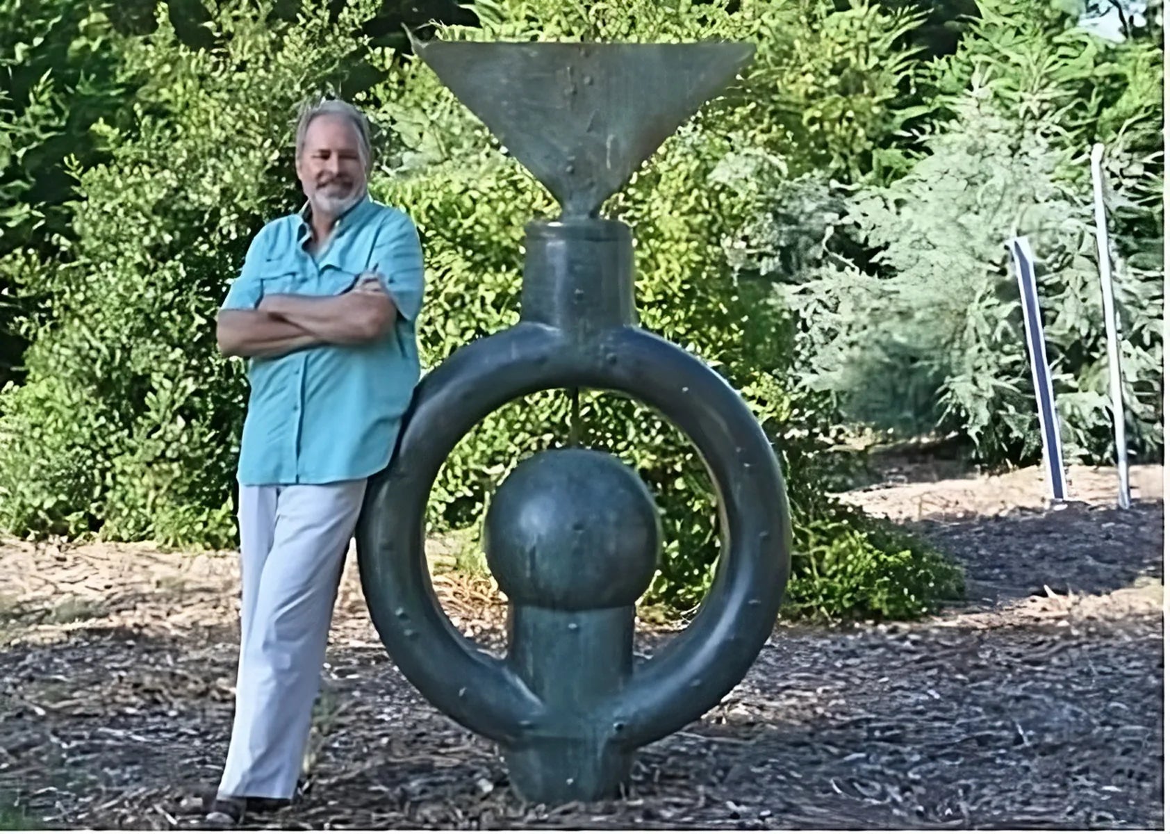 Marc Staples leaning against his sculpture titled Omega Point