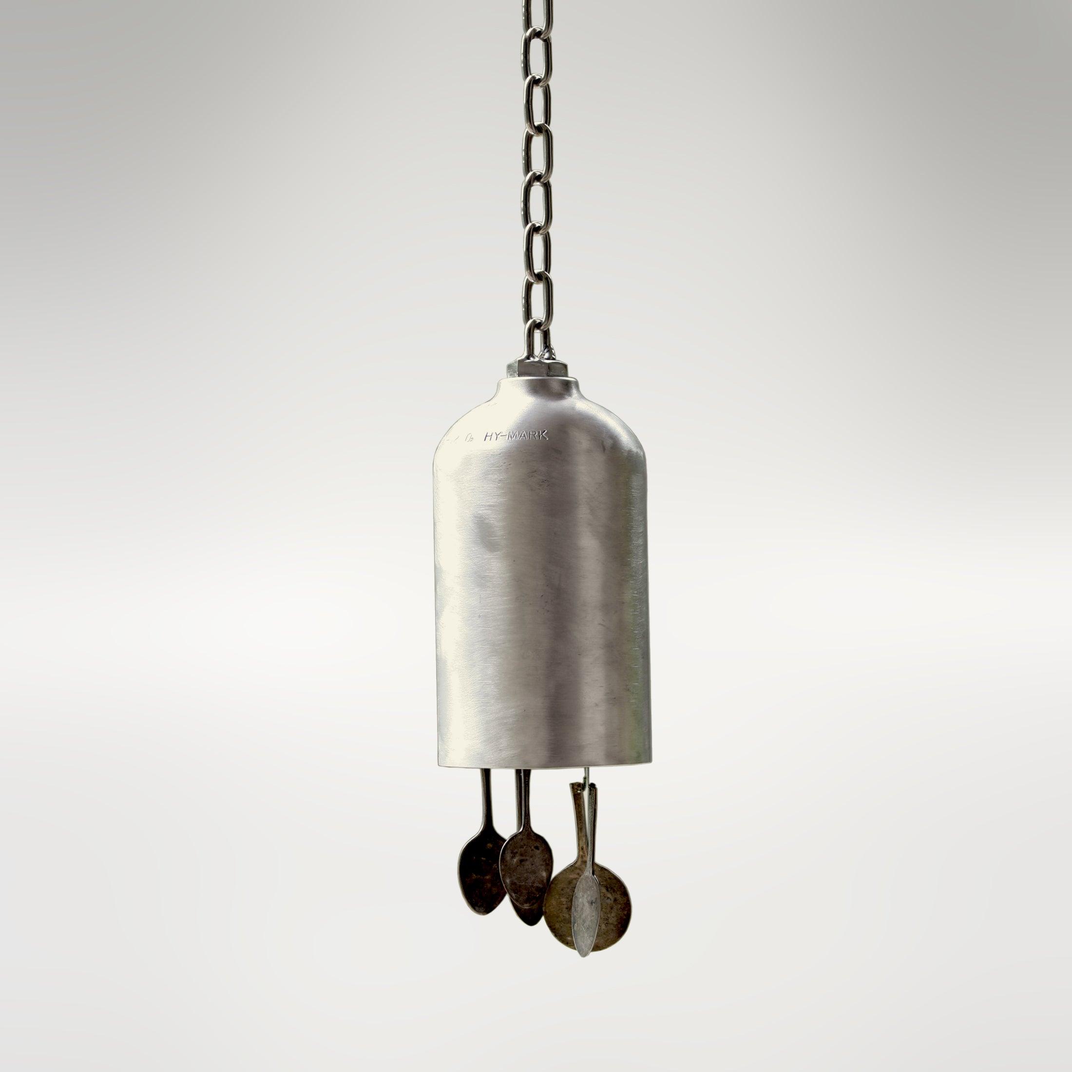 A wind bell made from a re-purposed oxygen tank and flattened spoons. It features a silvery tone and appearance.