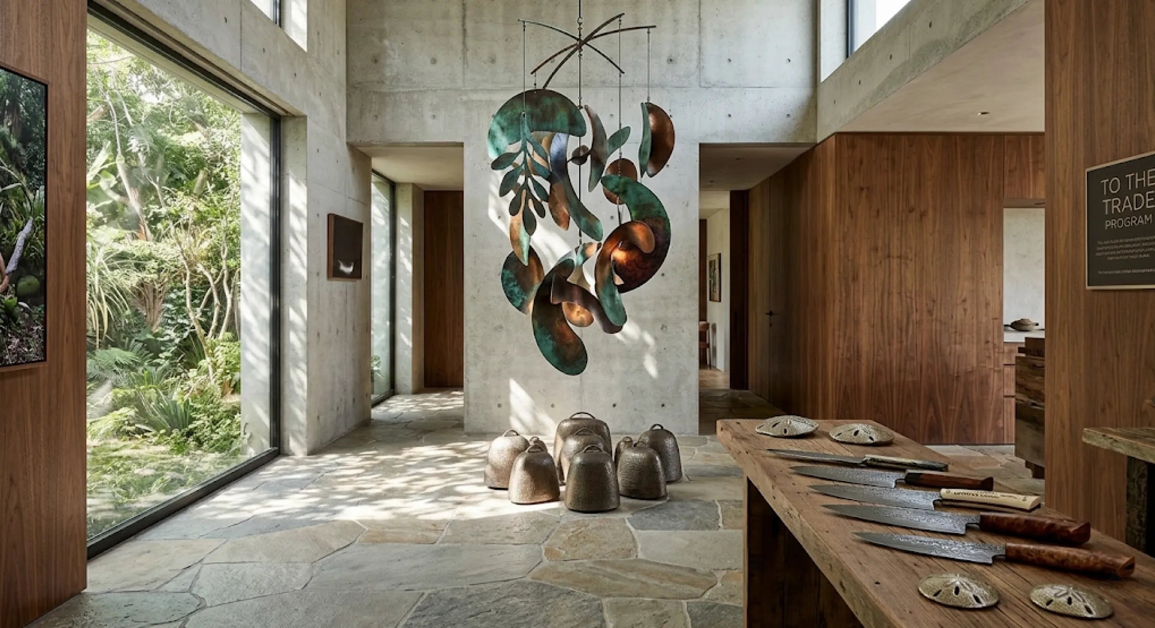 Biophilic interior design by Lago Luna Studio featuring a hand-hammered botanical kinetic mobile with green reactive patina, heavy-gauge architectural steel wind bells, and hand-forged Damascus steel knives by Master Craftsman Marc Staples.