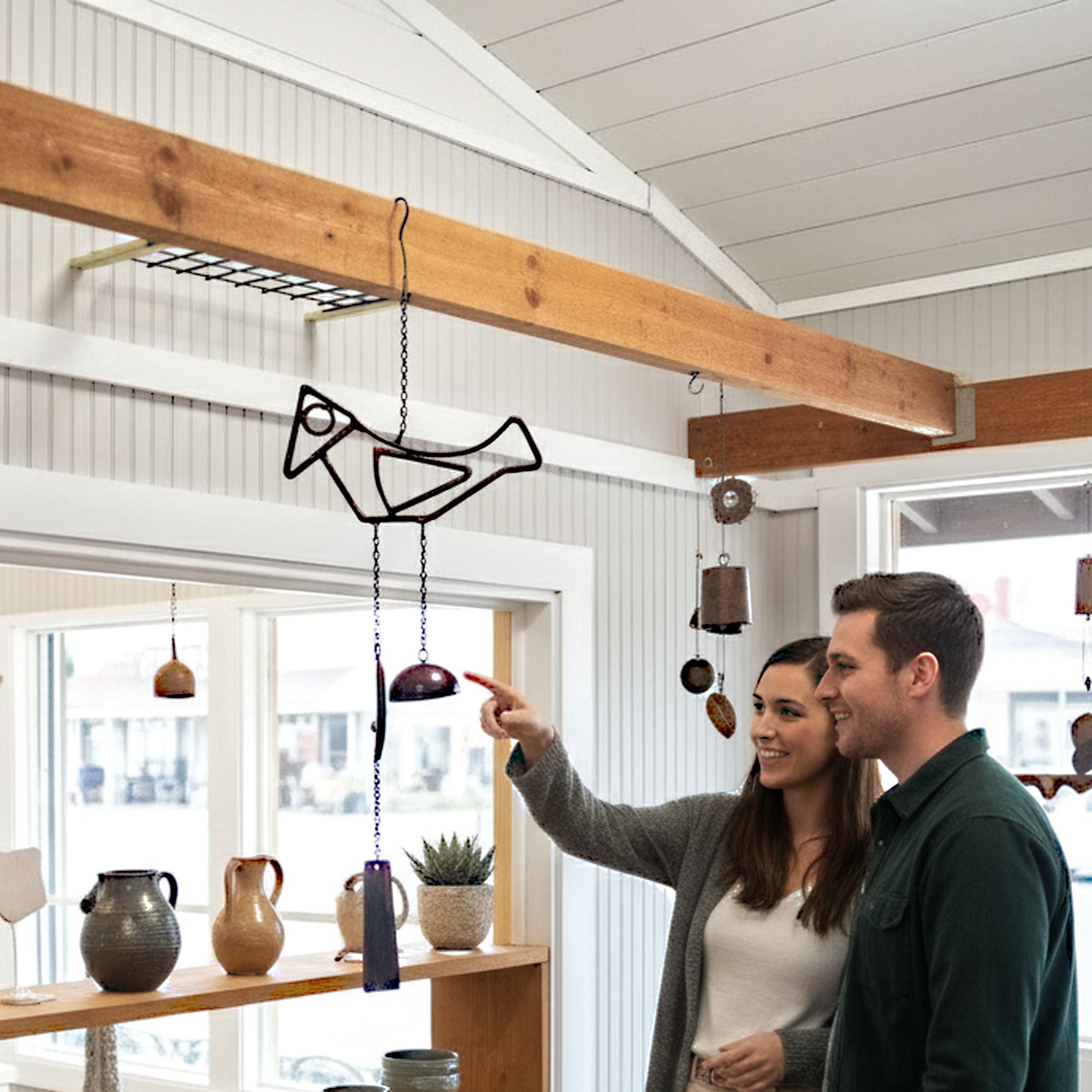 Couple in a modern interior space pointing at the Birdsong windchime.
