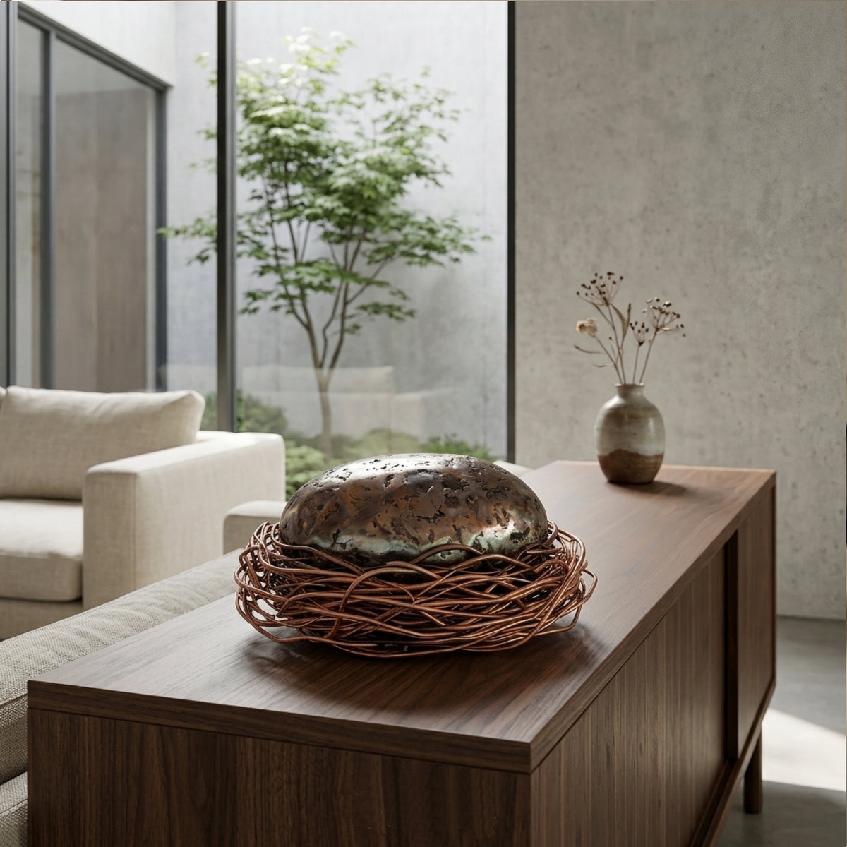 The Egg modernist metal sculpture with hand-coiled copper nest by Marc Staples on a walnut credenza in a modern living room.