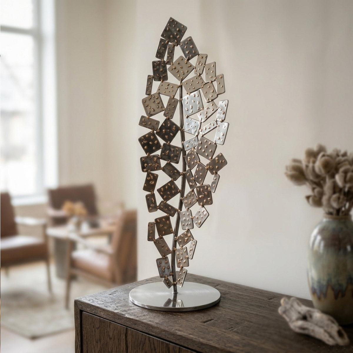 "Prometheus" metal sculpture featuring tiered rectangular plates in polished stainless steel accented with golden silicon bronze beads, displayed on a wooden cabinet.