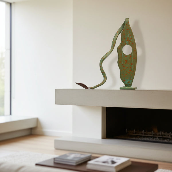 Abstract metal sculpture "Scoperta Terra" with green patina, serving as a statement piece on a fireplace mantel.